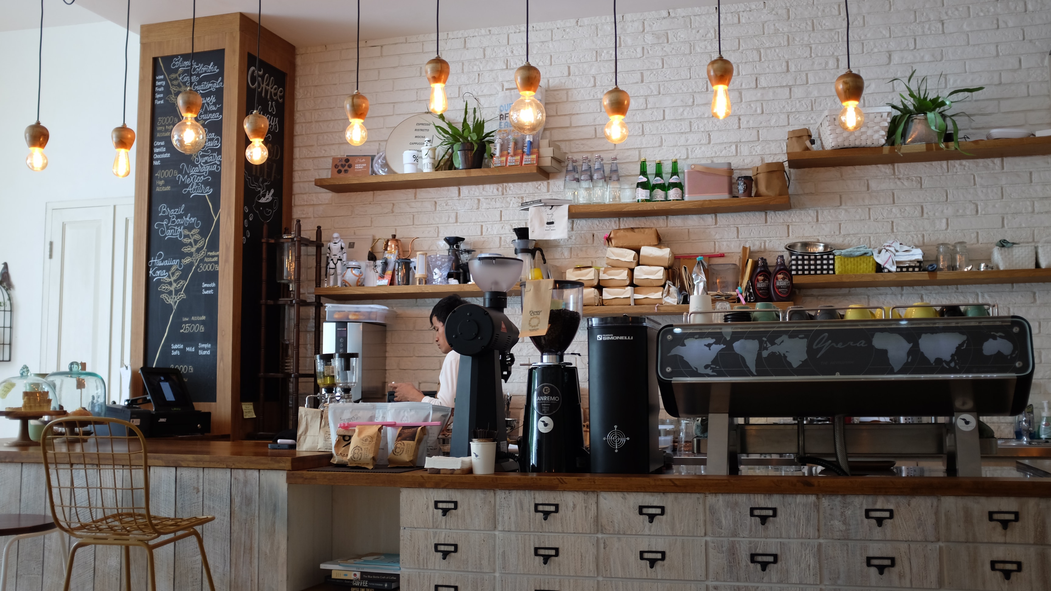 Image of cafe bar with one barista in the corner.