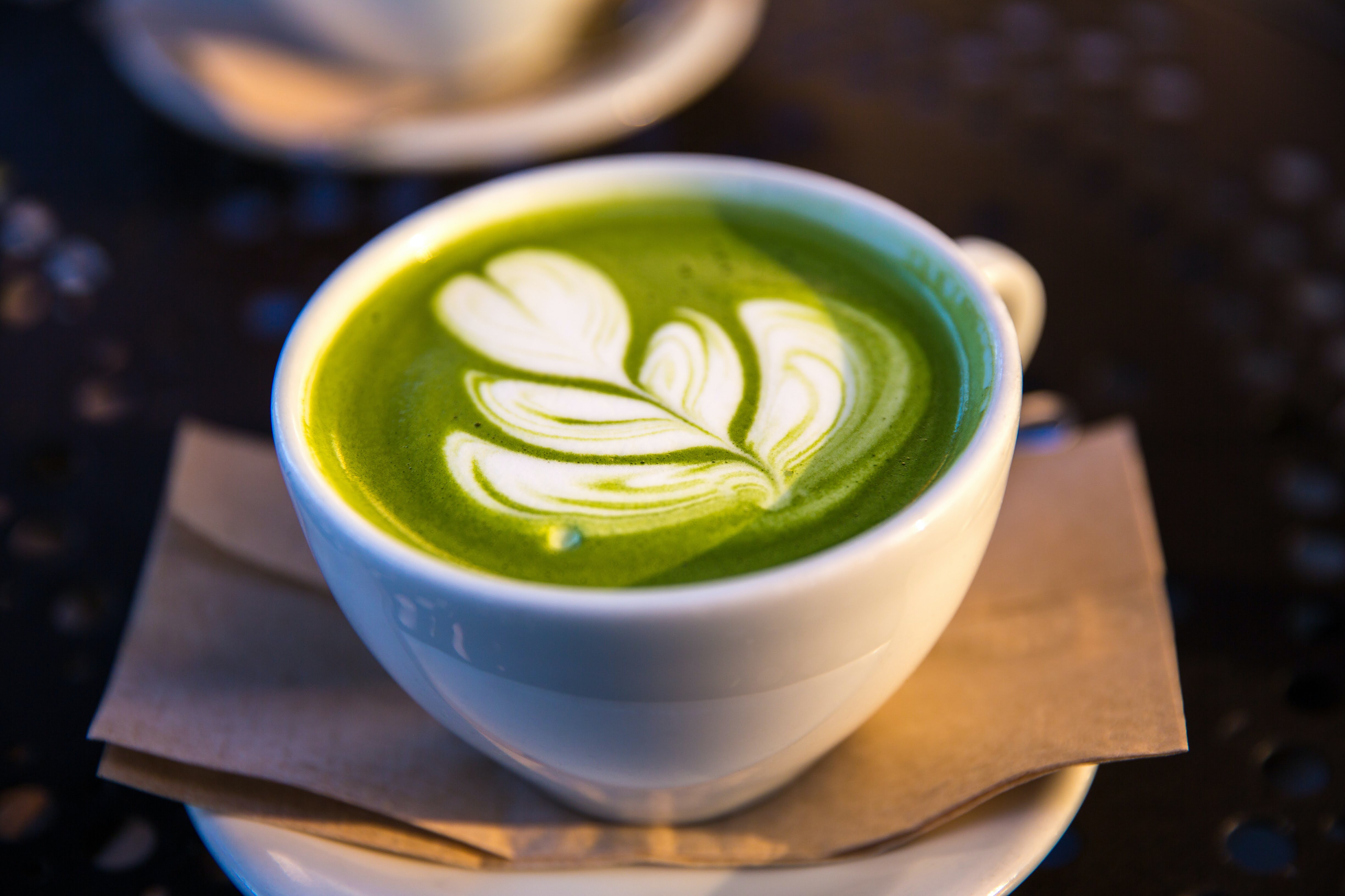 A green latte with white foam design.