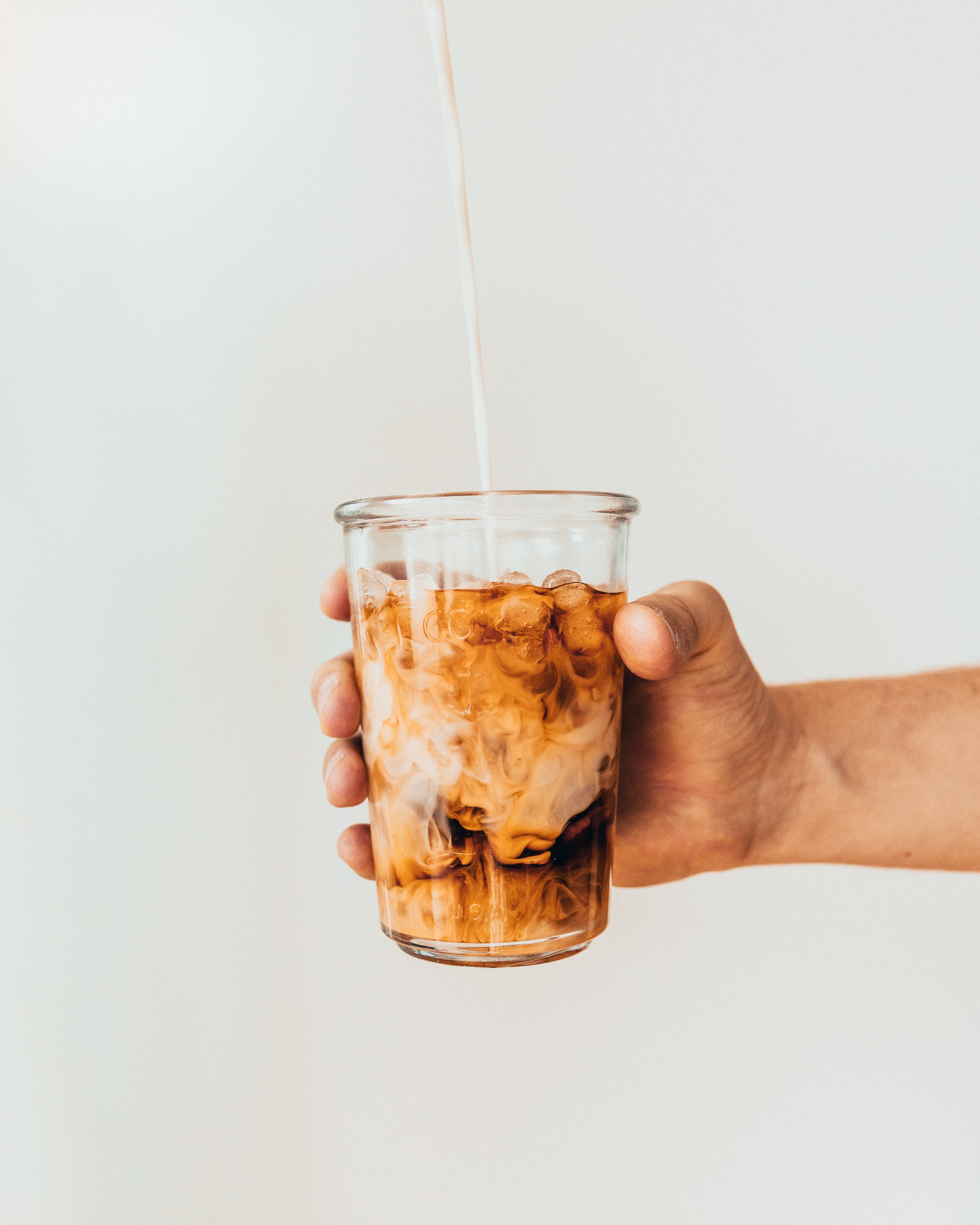 Hand holding light brown iced latte.