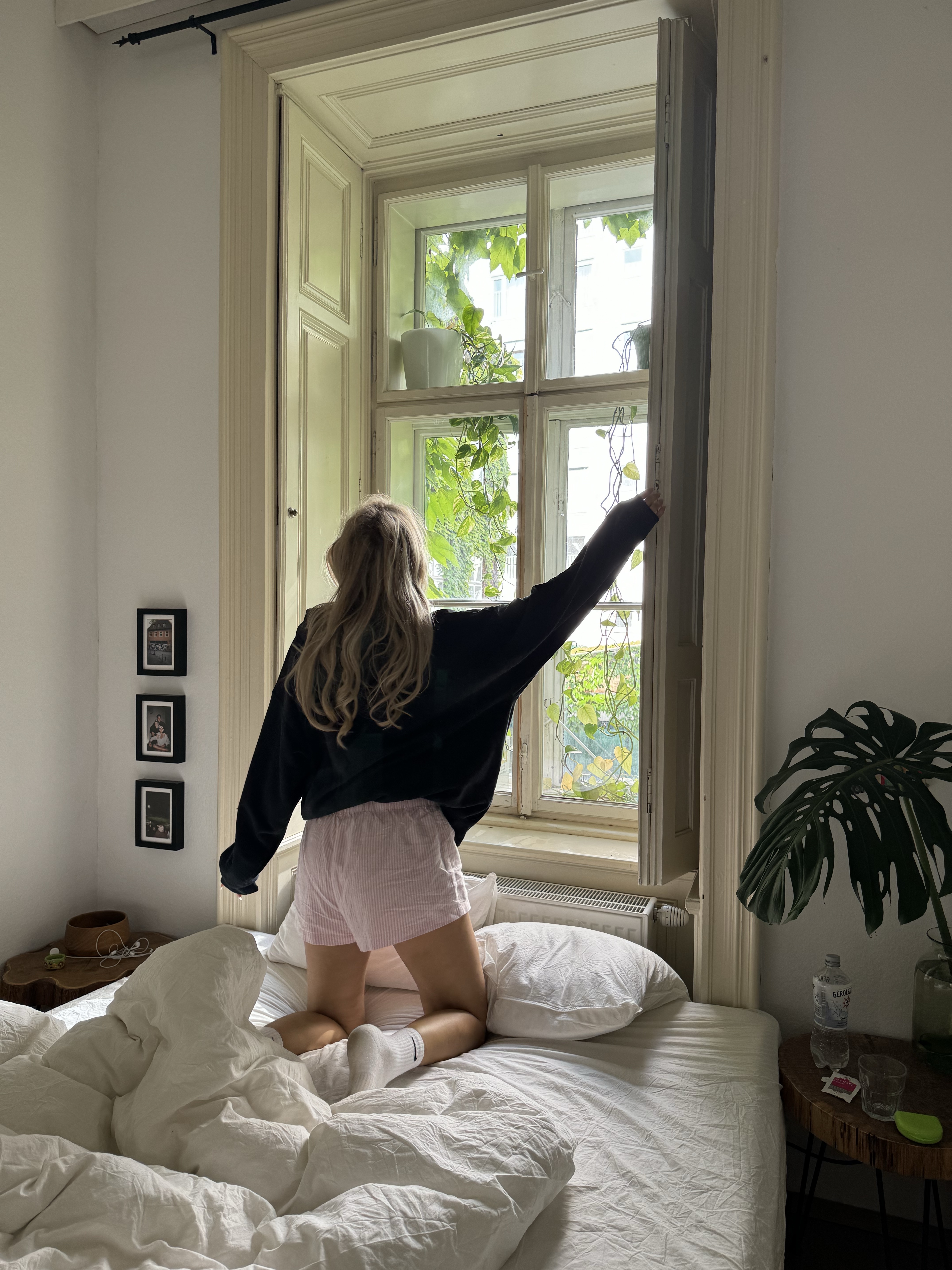 woman opening blinds in her bedroom